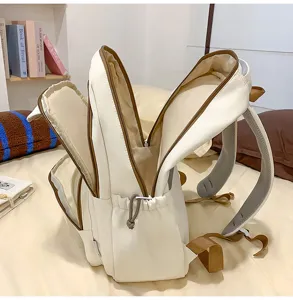 Detailed view of large capacity cream white school backpack with brown trim and multiple pockets.