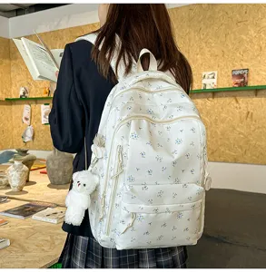Detailed view of a cute floral print canvas backpack with a small bear pendant for daily school.