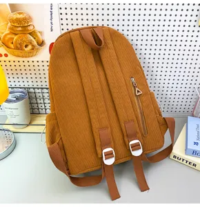 Detailed view of the brown corduroy backpack showing back straps, zipper pocket, and texture.