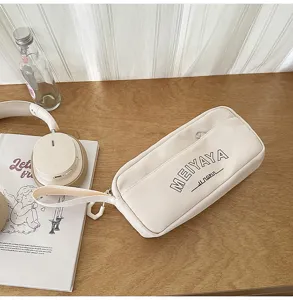 Detailed view of beige canvas pencil pouch with zipper and wrist strap on wooden desk.