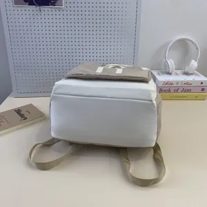 Detailed view of casual student backpack bottom, neutral beige and white canvas.
