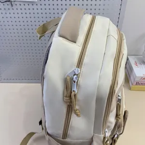 Detail view of a beige minimalist casual school backpack with multiple zippered compartments.