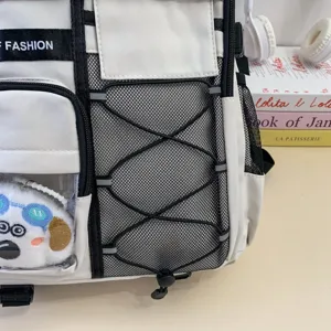Detailed view of fashionable white student backpack with mesh pocket and cute plush pendant.