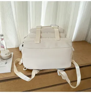 Detail view of the large capacity beige multi-pocket backpack with adjustable straps on wooden desk.