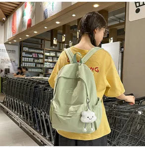 Detail view of light green casual backpack with cute cloud pendant in lifestyle shopping scene.