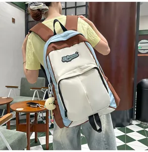 Color-blocked casual student backpack detail view, featuring front pocket and cute keychain.