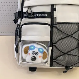 Detailed close-up of white student backpack featuring mesh side pocket and cute dog plush keychain.