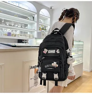 Detail view of a black casual large capacity backpack with multiple pockets and cute plush pendants.
