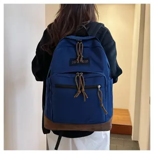 Detail shot of blue casual backpack with brown bottom and front zip pocket, daily travel bag.