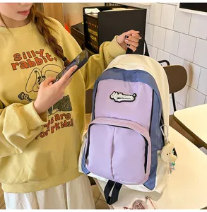 Detail shot of the contrast color student backpack with multiple pockets and cute pendant.