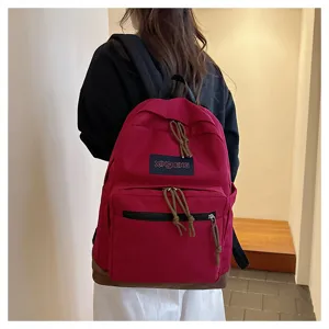 Detail view of casual canvas backpack with suede bottom and front pocket in indoor setting.