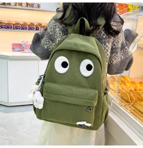 Cute green corduroy backpack with big googly eyes detail, perfect for casual daily use.