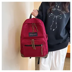 Detailed view of the red canvas casual backpack showing front pocket and drawstring design.