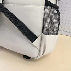 Close-up detail of white student backpack featuring durable black straps and mesh side pocket.