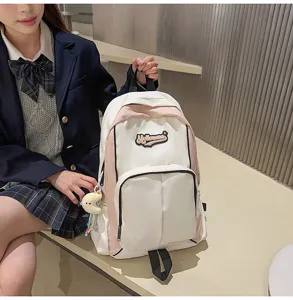 Close-up detail of the pink and white student backpack with custom patch and zipper pocket.
