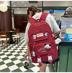 Detailed view of large capacity backpack with cute plush pendants and multiple front zipper pockets.
