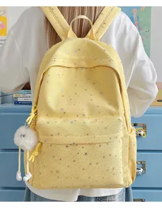 Detailed view of the cute yellow star backpack with fluffy pom-pom pendant in cozy room.