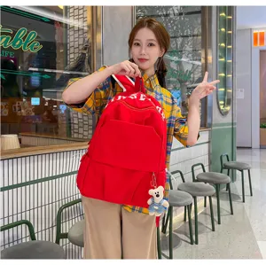 Detailed view of casual red nylon school backpack with cute bear pendant in cafe setting