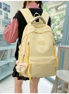 Detailed view of casual yellow student backpack with cute plush bear pendant and multi-pockets.