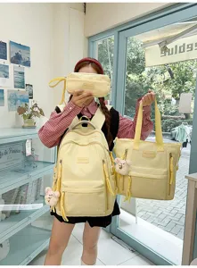 Detailed view of yellow student backpack set with tote bag and cute bear pendant for daily use.