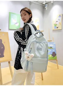 Detailed view of light blue school backpack with cute bear pendant and spacious design.