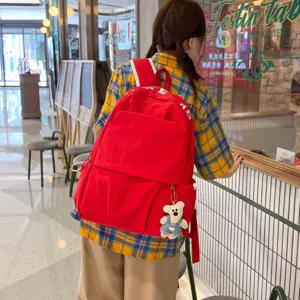 Casual red nylon backpack for women, large capacity student school bag with cute bear pendant.