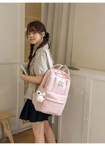 Casual pink backpack detail view featuring durable fabric, front pocket, and cute plush charm.