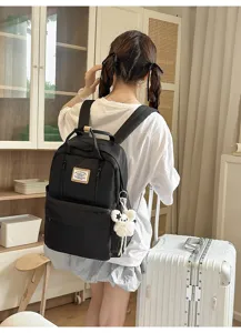 Black canvas backpack detail view, featuring cute bear pendant and large capacity for school.
