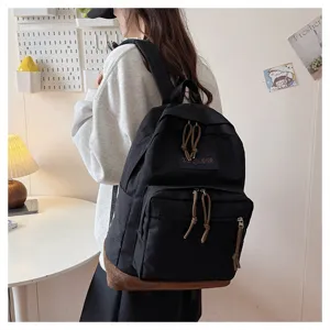 Detail shot of black canvas backpack with suede bottom and rope zipper pulls, lifestyle view.