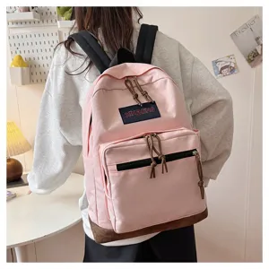 Casual pink canvas backpack with brown suede bottom, stylish school bag for students.
