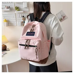 Stylish pink canvas school backpack for students with brown suede bottom and front pocket.