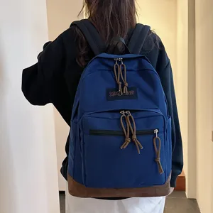 Classic blue canvas backpack with suede bottom worn on back, casual travel school bag