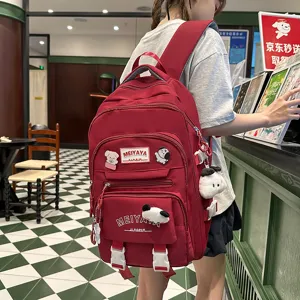 Large capacity red casual backpack for travel and school with cute plush pendants and pockets.