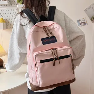 Casual pink canvas backpack with suede bottom and front pocket for daily school and travel use.