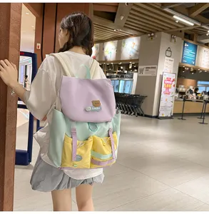 Detailed view of color-block casual backpack with cute bear badge and multi pockets.