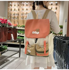 Detailed view of the color-blocked canvas backpack showing cute bear patch and pockets.
