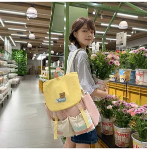 Detail view of the colorful color-blocked backpack with cute bear patch worn in store.