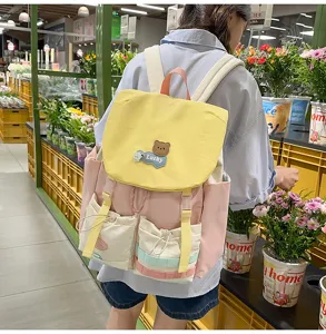 Color-blocked canvas backpack featuring a cute bear patch and multi-pocket casual daily style.