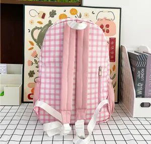 Detail showcase of the pink and white gingham student backpack back straps and side zipper pocket.