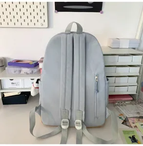 Backpack rear view showing straps, zipper pocket, and side pouch details on desk setup