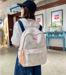 Women pink textured backpack casual large capacity school bag with cute bear pendant and top handle.