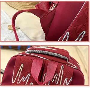 Red backpack detail view featuring embossed monogram pattern and colorful embroidery lines.