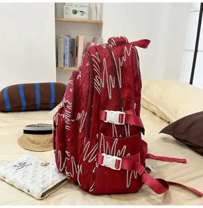 Large capacity red student backpack with stylish white embroidery design for daily use.