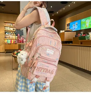 Pink multi-compartment casual backpack detail, featuring embroidery texture and cute plush pendant.