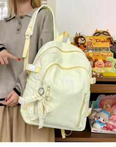 Detailed shot of cute aesthetic yellow nylon backpack with lace bow pearl pendant, multi pockets