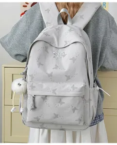 Detail view of a minimalist grey backpack with butterfly prints and fluffy keyring accessory.