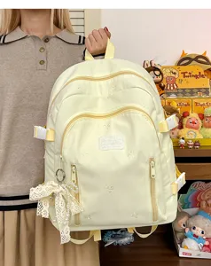 Cute embroidered light yellow backpack detail, featuring lace bow pendant and multi-pocket design.