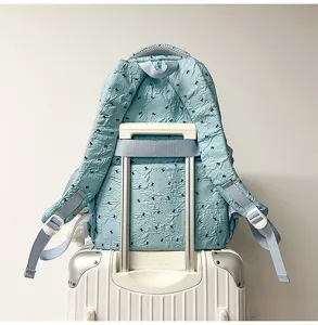 Detail view of light blue travel backpack with crinkled texture and luggage strap feature.