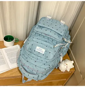 Detail view of light blue textured casual backpack with multiple compartments and cute pattern.