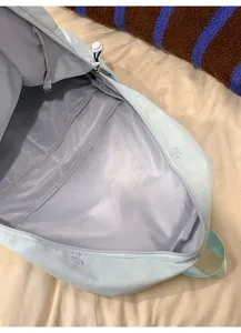 Light blue backpack interior detail, zipper compartment, cute bow embroidery, casual daypack.